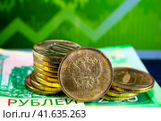 Монеты банка России на двухсот-рублевой купюре на не резком фоне графика курса валют (2023 год). Редакционное фото, фотограф Анна Аникова / Фотобанк Лори