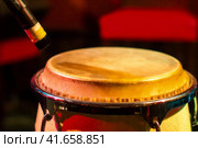 Traditional ethnic Cuban conga drum on red background. Musical instrument made of wood covered with leather and microphone. Ethnic drum set at a concert of jazz music. Стоковое фото, фотограф Андрей Журавлев / Фотобанк Лори