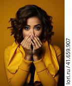 A girl in a yellow jacket covers her hands with fright. Generated by AI. Стоковое AI-изображение, AI-художник Ярославский Максим / Фотобанк Лори