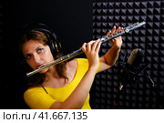 Record wind musical instruments with a professional microphone. Girl flute player in headphones plays in recording studio. Woman flutist playing the transverse flute. Стоковое фото, фотограф Андрей Журавлев / Фотобанк Лори