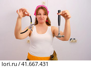 Woman builder holds construction tools with disgust and disdain. Стоковое фото, фотограф Андрей Журавлев / Фотобанк Лори