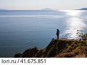Женщина стоит на вершине скалистого берега моря. Красивый морской пейзаж. Женщина смотрит на море с берега. Путешествия и туризм на Дальнем Востоке России. Охотское море, Магаданская область, Россия. Осень. Стоковое фото, фотограф Андрей Степанов / Фотобанк Лори