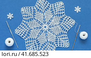 Video of beautiful hand crocheted lace doily in shape of Christmas snowflake on blue background with skeins of cotton yarn and crochet hooks. Winter crafts and handmade gifts concept. Flat lay, close-up. Стоковое видео, видеограф Виктория Катьянова / Фотобанк Лори