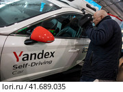 Посетитель выставки смотрит беспилотный автомобиль компании Яндекс в павильоне выставки во время проведения Международной выставки-форума "Россия" на территории выставочного комплекса ВДНХ в городе Москве, Россия (2023 год). Редакционное фото, фотограф Николай Винокуров / Фотобанк Лори