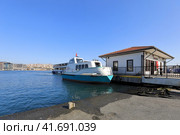 Modern building of the Fener ferry pier on the shore of the Golden Horn. Vessel standing on the pier. District of Fatih, city of Istanbul, Turkey. (2023 год). Редакционное фото, фотограф Bala-Kate / Фотобанк Лори