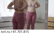 A woman tries on a bra in the fitting room, a bustier with a wide clasp is reflected in the mirror. Стоковое видео, видеограф Станислав Тарко / Фотобанк Лори