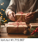 An unrecognizable woman wraps Christmas gifts in craft paper. Стоковое AI-изображение, AI-художник Margarita Davchenko / Фотобанк Лори
