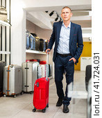 Positive man chose suitcase in haberdashery store. Стоковое фото, фотограф Яков Филимонов / Фотобанк Лори
