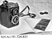 Пленочный фотоаппарат "Любитель 2" и хранящиеся в тетради негативы формата 6х6 см кв. Черно-белое изображение. (2023 год). Редакционное фото, фотограф Владимир Литвинов / Фотобанк Лори