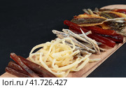 Salty snacks with beer and ale. Dried fish, squid, delicacies. Close-up on a black background. Стоковое фото, фотограф Bogdanova Mariia / Фотобанк Лори