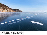 Winter landscape with an ice field of pure snowless blue ice on shore of frozen Lake Baikal near village of Goloustnoye on frosty sunny January day. Natural background. Winter travel and outdoors. Стоковое фото, фотограф Виктория Катьянова / Фотобанк Лори