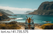 A woman next to a car traveling on the road with her hands raised, a car on the shore near a deserted beach. Generated by AI. Стоковое AI-изображение, AI-художник Ярославский Максим / Фотобанк Лори