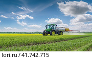Watering, treating fields with crops with Pesticides and Herbicides on a tractor. Agricultural industry. Стоковое AI-изображение, AI-художник Ирина Ручушкина / Фотобанк Лори