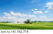 Watering, treating fields with crops with Pesticides and Herbicides on a tractor. Agricultural industry. Стоковое AI-изображение, AI-художник Ирина Ручушкина / Фотобанк Лори