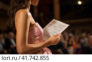a young woman in an evening dress with a program for a concert in her hands. Стоковое AI-изображение, AI-художник Margarita Davchenko / Фотобанк Лори