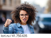 A young girl with curly hair rejoices in luck with her fists raised up. Generated by AI. Стоковое AI-изображение, AI-художник Ярославский Максим / Фотобанк Лори