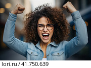 A young girl with curly hair rejoices in luck with her fists raised up. Generated by AI. Стоковое AI-изображение, AI-художник Ярославский Максим / Фотобанк Лори