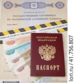 Государственный сертификат материнский (семейный) капитал, российский паспорт, деньги и оградительная лента с надписью "уголовная ответственность" (2023 год). Редакционное фото, фотограф Цибаев Алексей / Фотобанк Лори