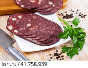 Close up of Spanish smoked blood sausage on white plate on wooden table. Стоковое фото, фотограф Яков Филимонов / Фотобанк Лори