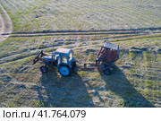 Hay harvesting. A single tractor with a baler in a pasture with swaths of cut grass. Drone footage. Стоковое фото, фотограф Роман Дзюбало / Фотобанк Лори