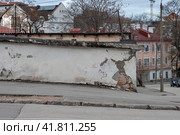Вид на пустую городскую улицу и потрескавшуюся старую стену. На тротуаре никого. Стоковое фото, фотограф Андрей Степанов / Фотобанк Лори