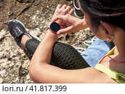 Latin woman, middle-aged, resting, regaining strength, eating, drinking water, after a gym session, burning calories, keeping fit, outdoors by the sea, wearing headphones and smart watch. Стоковое фото, фотограф carlos l vives / Фотобанк Лори