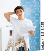 Young man owner is shocked by the estimate for the renovation of cottage. Стоковое фото, фотограф Яков Филимонов / Фотобанк Лори
