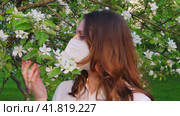 Pregnant woman in medical face mask n95 with apple tree flowers in spring nature. Happiness of pregnancy during covid epidemic, coronavirus pandemic quarantine. Стоковое видео, видеограф Андрей Журавлев / Фотобанк Лори