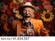 Portrait of overjoyed old eccentric senior man in orange suit dancing in front of a colorful flowers background. Expressing joy and free spirit, beauty of aging and individuality and carelessness. Стоковое AI-изображение, AI-художник Ирина Михайличенко / Фотобанк Лори