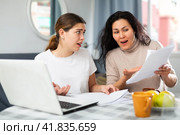 Two women with financial documents near laptop sitting at table at home. Стоковое фото, фотограф Яков Филимонов / Фотобанк Лори
