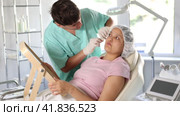 doctor calmly presents procedure's results to client using large mirror, highlighting visible improvements in her skin's radiance and youthfulness. Стоковое видео, видеограф Яков Филимонов / Фотобанк Лори