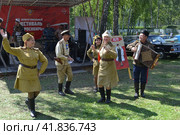 Женщины и мужчины в военной униформе танцуют под гармошку. Парад ретро автомобилей в музее-заповеднике Томская Писаница (2022 год). Редакционное фото, фотограф александр афанасьев / Фотобанк Лори