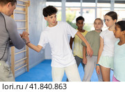 Self-defence course instructor demonstrating painful wristlock to teenagers. Стоковое фото, фотограф Яков Филимонов / Фотобанк Лори