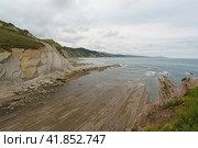 The seascape in Basque Autonomous Community in summer cloudy day. Wide Atlantic ocean beach surrounded by mountains at low tide in Bay of Biscay. Charming Zumaia Algorri beach. Стоковое фото, фотограф YuryKara / Фотобанк Лори