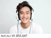 Smiling asian young man in white tee shirt listening music with white headphones on white. Close up. Стоковое AI-изображение, AI-художник Наталья Семкина / Фотобанк Лори