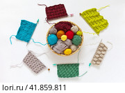 Circular composition of various samples of simple knitting with "knit" and "purl" loops on needles and set balls of multicolored wool yarn in wicker basket. Knitting School. Top view, close-up, flat lay. Стоковое фото, фотограф Виктория Катьянова / Фотобанк Лори