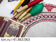 Крупным планом сборник стихов Сергея Есенина, коклюшки с разноцветными нитками и михайловское кружево лежат на столе (2023 год). Редакционное фото, фотограф Николай Винокуров / Фотобанк Лори