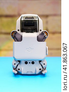 Квадрокоптер Dji Mini 2 со сложенными и зафиксированными лапками с моторами на голубом столе во время запрета на полеты дронов (2023 год). Редакционное фото, фотограф Sergei Gorin / Фотобанк Лори