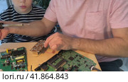 Father with his son spend time together. Close-up of a man teaching his boy at home to solder computer spare parts. Education moment during parenthood. Togetherness concept. Стоковое видео, видеограф Ирина Старикова / Фотобанк Лори