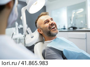 Happy patient with open mouth showing teeth in dental chair in dentist's office clinic. Стоковое AI-изображение, AI-художник Коханова Наталья / Фотобанк Лори