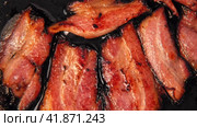 Frying Bacon Slices in a Pan. Crispy Pieces of Delicious Red Thin Smokey Bacon Fried in a Hot Skillet. Traditional Breakfast. Smoked Bacon Rasher or Strip Being Cooked. Grill. Fat High Calorie Food. Стоковое видео, видеограф Марина Демидюк / Фотобанк Лори