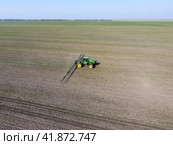 Tractor with hinged system of spraying pesticides. Fertilizing with a tractor, in the form of an aerosol, on the field of winter wheat. Стоковое фото, фотограф Леонид Еремейчук / Фотобанк Лори