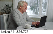 Senior Grey haired 60s - 70s Aged man sitting at table, looking at laptop at home. Older Smile Man working, watching news, content. Old People using modern technology concept, e-learning, education. Стоковое видео, видеограф Марина Демидюк / Фотобанк Лори