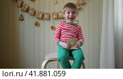 Boy in pajamas, Santa cap eating sweet candy on paper advent calendar with presents background. Little happy child with gift of handmade Christmas calendar on wall. Celebrating at home Xmas tradition. Стоковое видео, видеограф Марина Демидюк / Фотобанк Лори