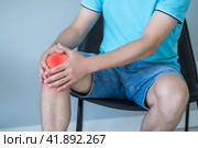 Knee pain, man suffering from ache and doing self-massage at home. Стоковое фото, фотограф Станислав Тарко / Фотобанк Лори