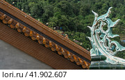A fragment of the pagoda Ban Pa That roof decoration. An elegantly curved stone curl with carved petals against the thicket of a tropical forest. Close-up. Malaysia. Penang. Kek Lok Si Temple (2023 год). Стоковое фото, фотограф Вера Ивановна Кубарева / Фотобанк Лори