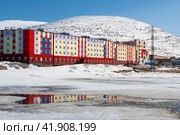 City in the far north in the Arctic. Colorful buildings on the background of snow-capped mountains. The end of May in the Arctic. Pevek is the northernmost city in Russia. Chukotka, Siberia, Russia. Стоковое фото, фотограф Андрей Степанов / Фотобанк Лори