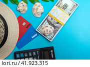 Платежные карты МИР и VISA с соломенной шляпой пачкой долларов и калькулятором на голубом фоне. Концепция отпускных расходов. (2024 год). Редакционное фото, фотограф Ярославский Максим / Фотобанк Лори