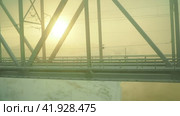 Volkhov, Russia, January 2, 2024: driving along the railway bridge over the Volkhov River next to the hydroelectric power station. Severe frost -30 degrees Celsius. Low polar sun. Yellow cold fog. Редакционное видео, видеограф Юлия Петровская / Фотобанк Лори