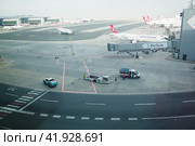 Istanbul, Turkey 01.01.24: Runway. The territory of the international airport IST Havalimani. Cars, trucks, cars are moving. Telescopic bridge or hose for disembarking and embarking passengers. Редакционное фото, фотограф Юлия Петровская / Фотобанк Лори